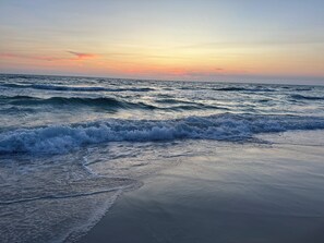 Ein Strand mit Wellen und einem Sonnenuntergang.