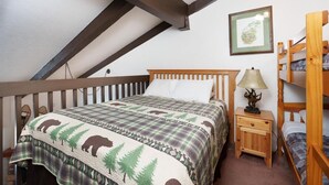 A bedroom with a bed, a nightstand, a lamp, and a bunk bed. - (B210) Loft Condominiums (Yosemite National Park)