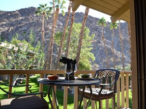 Ein Balkon mit Tisch für zwei Personen, mit Blick auf eine Berglandschaft mit Palmen.