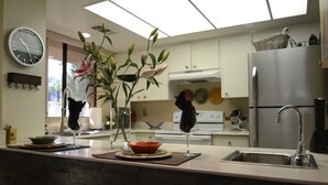 A modern kitchen with a central island, a refrigerator, and a clock on the wall.