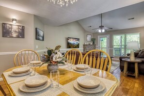 A dining area with a wooden table set for four, surrounded by wooden chairs.
