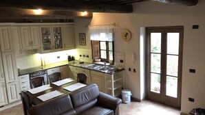A kitchen with a dining area, a brown leather sofa, and a wooden ceiling. - Beautiful house near San Gimignano in Tuscany with views, pool,garden, A/C, WiFi (Gambassi Terme, FI)