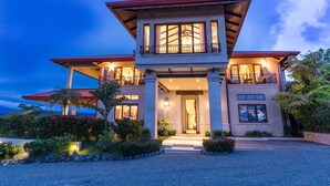A two-story house with a prominent entrance, large windows, and a well-lit balcony. - Platinum - A New level of Luxury, with 360 degree views & unmatched quality (Quepos)