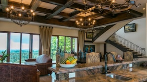A spacious living area with a large window, a chandelier, and a fruit bowl on the island. - Platinum - A New level of Luxury, with 360 degree views & unmatched quality (Quepos)