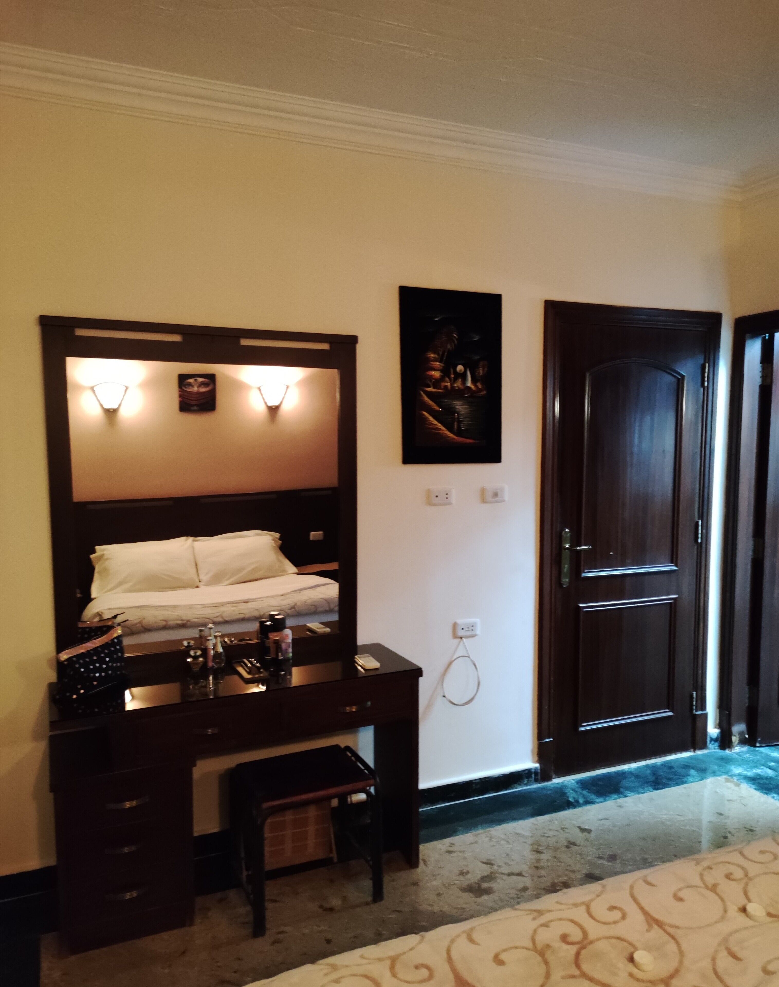 A hotel room with a bed, a dresser, a mirror, and a door.
