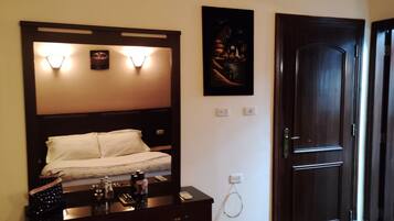 Ein Hotelzimmer mit einem Bett, einem Schminktisch, einem Spiegel und einer Tür.