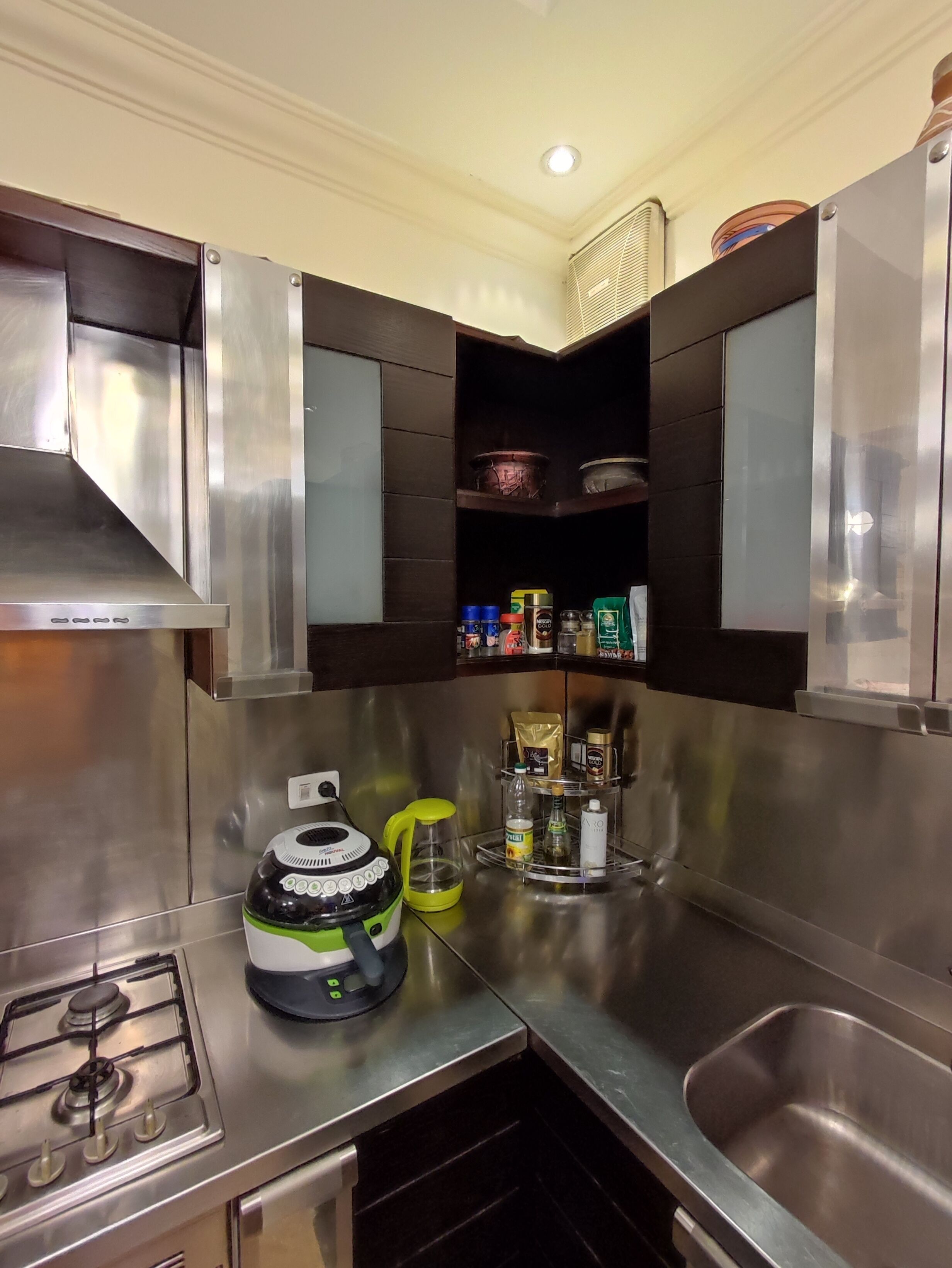 A modern kitchen with stainless steel appliances, a gas stove, a coffee maker, and a spice rack.