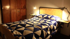 Un dormitori amb llit, armari de fusta i dues làmpades de nit.