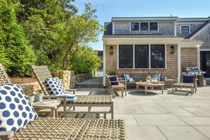 An outdoor patio with wicker furniture, a barbecue grill, and a stone wall. - Gorgeous Home 2 Min Walk to Beach! (Harwich Port)