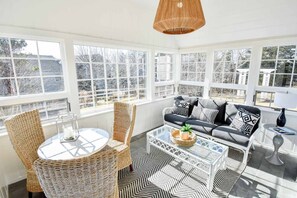 A sunlit room with a sofa, two wicker chairs, a glass coffee table, and a patterned rug. - Gorgeous Home 2 Min Walk to Beach! (Harwich Port)