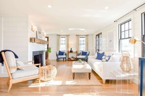 A spacious living room with a fireplace, two sofas, a coffee table, and a dining area with chairs. - Gorgeous Home 2 Min Walk to Beach! (Harwich Port)