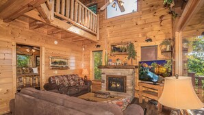 A cozy log cabin interior with a fireplace, leather sofas, and a television. - 🐾Paradise Point 🏔️LeConte Views, Hot Tub, Resort Pool! Near Attractions! (Sevierville)