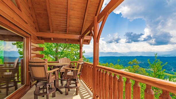 A wooden deck with a table and chairs, overlooking a mountainous landscape. - 🐾Paradise Point 🏔️LeConte Views, Hot Tub, Resort Pool! Near Attractions! (Sevierville)