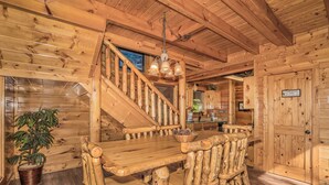 A wooden cabin interior with a staircase, a dining table, and a kitchen area. - 🐾Paradise Point 🏔️LeConte Views, Hot Tub, Resort Pool! Near Attractions! (Sevierville)