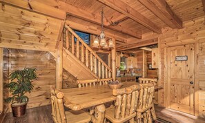 A wooden cabin interior with a staircase, a dining table, and a kitchen area. - ParadisePoint: SpectacularView, PetFriendly, HotTub, Wifi, ResortPool! Near Attractions! (Sevierville)