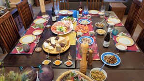 Een eettafel gedekt met diverse gerechten, glazen en toevoegingen, omringd door houten stoelen.