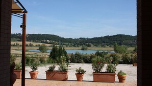 Een terras met terracotta plantenbakken en uitzicht op een meer en heuvels.