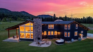 Una casa moderna con chimenea de piedra, ventanas amplias y un patio cubierto.