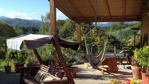 A wooden outdoor seating area with a hammock, a bench, and potted plants. - Podere la Piana-Cedro (fivizzano)