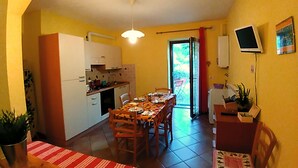 Une cuisine compacte avec des meubles blancs, une table à manger avec des chaises et un banc.
