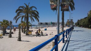 Una playa con palmeras, sombrillas y gente.