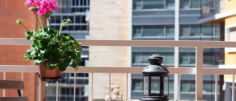 Un balcón con una maceta colgante y un farol sobre una mesa de madera.