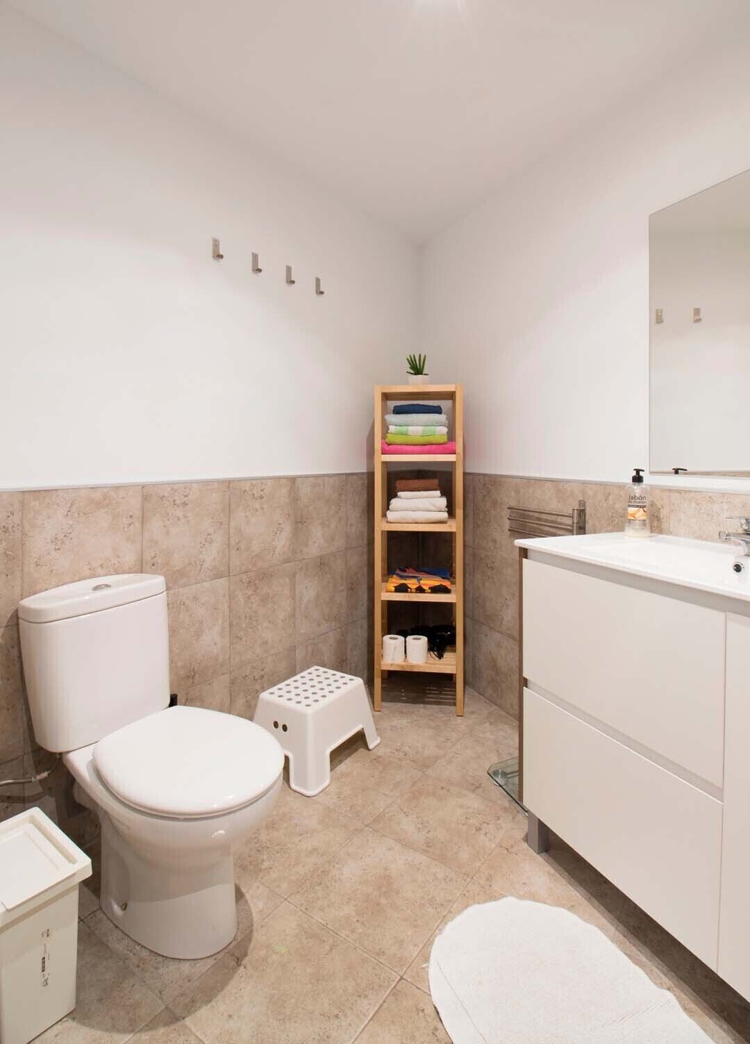 Een badkamer met toilet, wastafel en een plank met opgevouwen handdoeken.