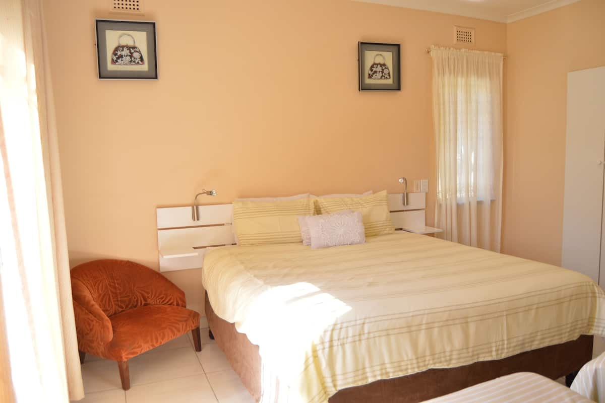 A bedroom with a bed, a chair, and two framed pictures on the wall.