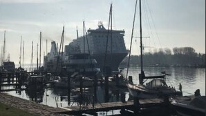 Ein Yachthafen mit einem großen Schiff am Kai, umgeben von kleineren Booten.