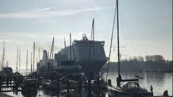 Ein Yachthafen mit einem großen Schiff am Kai, umgeben von kleineren Booten.