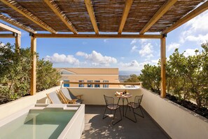 Terraza en la azotea con piscina, dos sillas, una mesa y una pérgola.