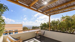 A rooftop terrace with a pool, lounge chairs, and a table. - Lemon Suites Santorini (Santorini)