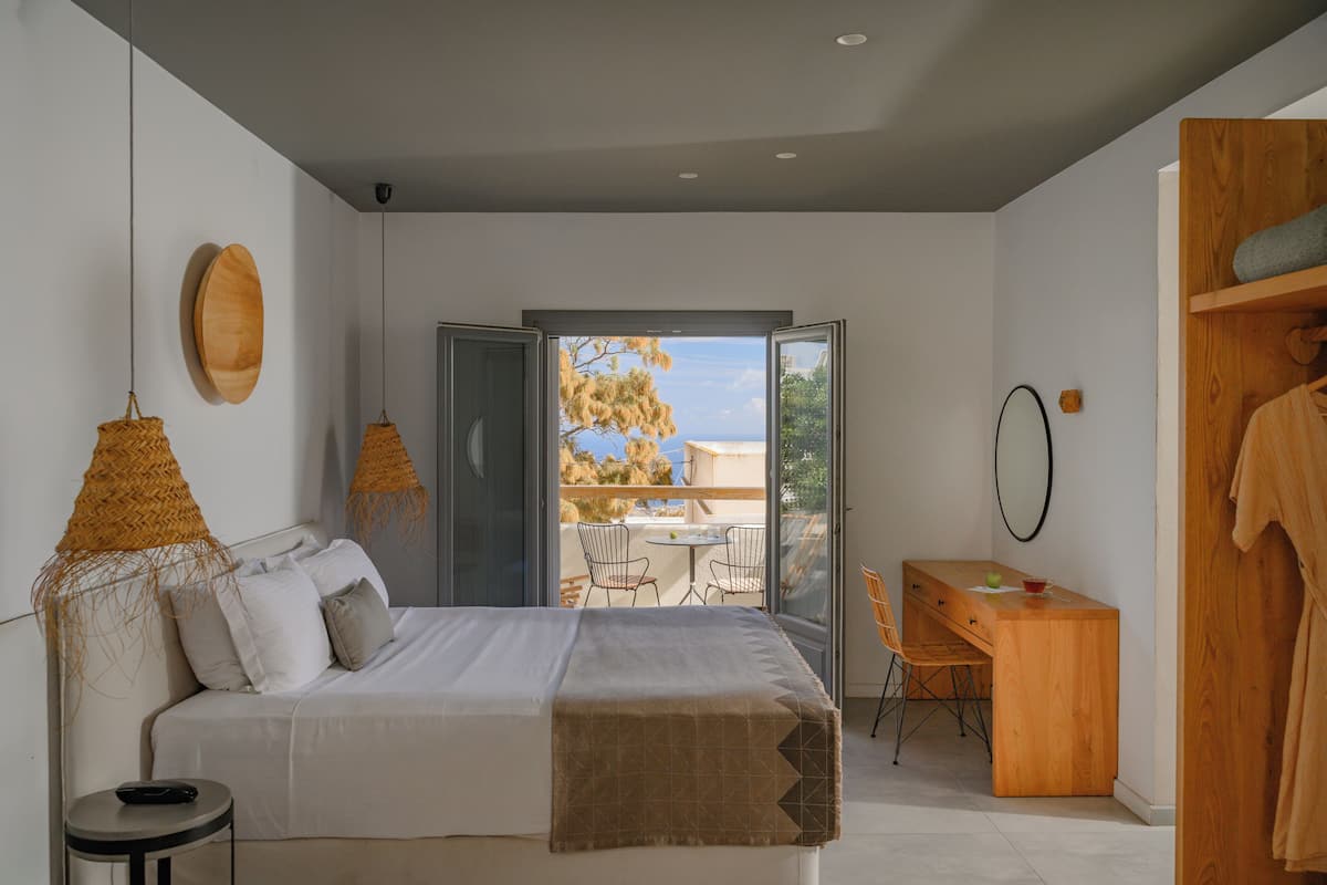 A bedroom with a bed, bedside table, and a view of the outdoors.