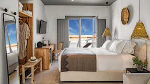 A modern bedroom with a large bed, a wooden desk, a chair, a small table, and a TV. - Lemon Suites Santorini (Santorini)
