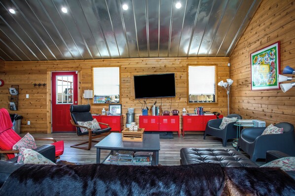A cozy cabin interior with a wooden interior, a television, and various seating arrangements.