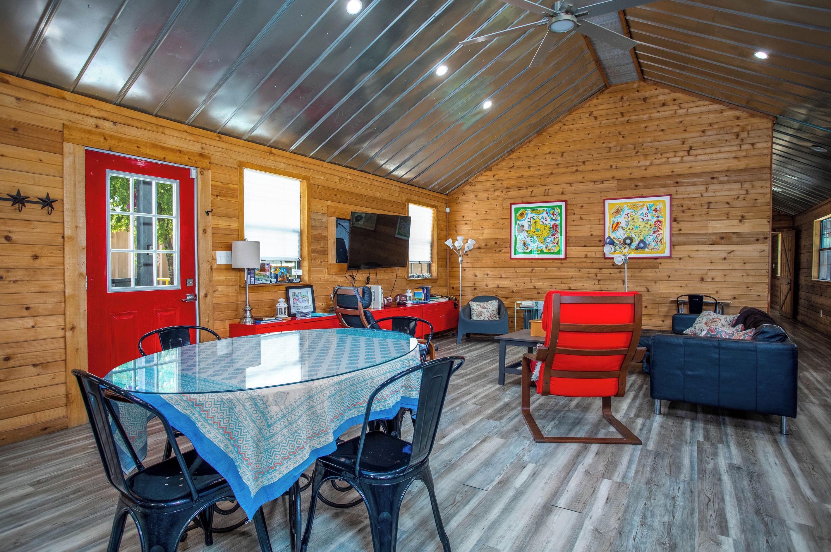 Een gezellig chalet interieur met een eethoek, een televisie en een rode deur.