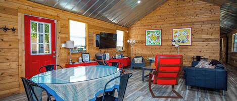 Een gezellig chalet interieur met een eethoek, een televisie en een rode deur.
