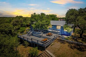 A two-story building with a deck and outdoor seating area, surrounded by trees. - Bandera Box Guesthouse (Bandera)