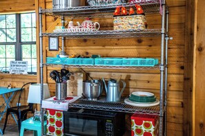 A kitchen with a microwave, a coffee maker, and various utensils on shelves. - Bandera Box Guesthouse (Bandera)