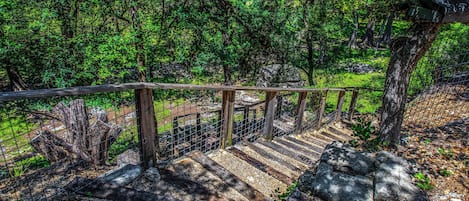 A wooden staircase with a metal railing leading through a forested area.