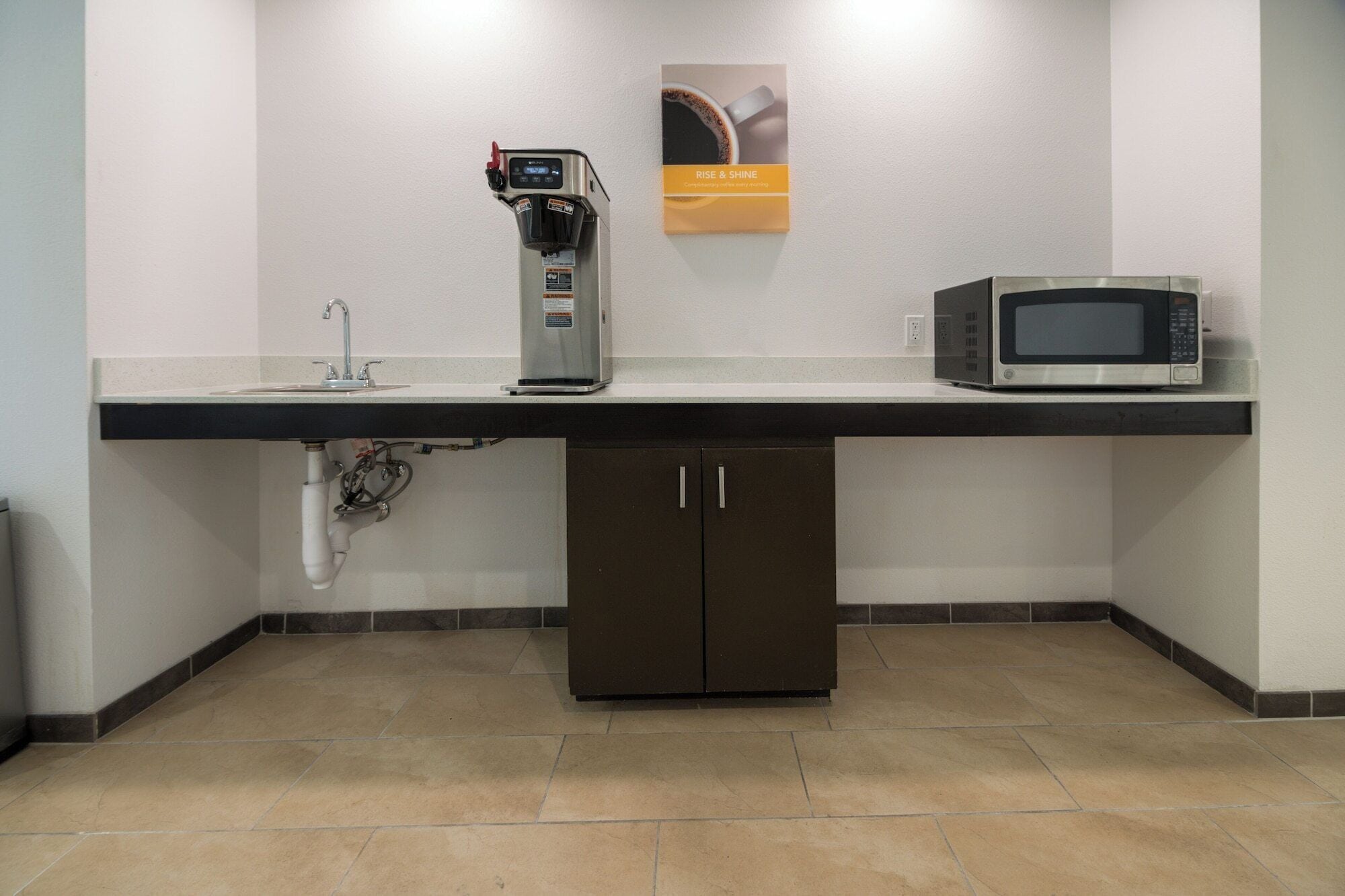 A kitchenette with a coffee machine, microwave, and a sink.