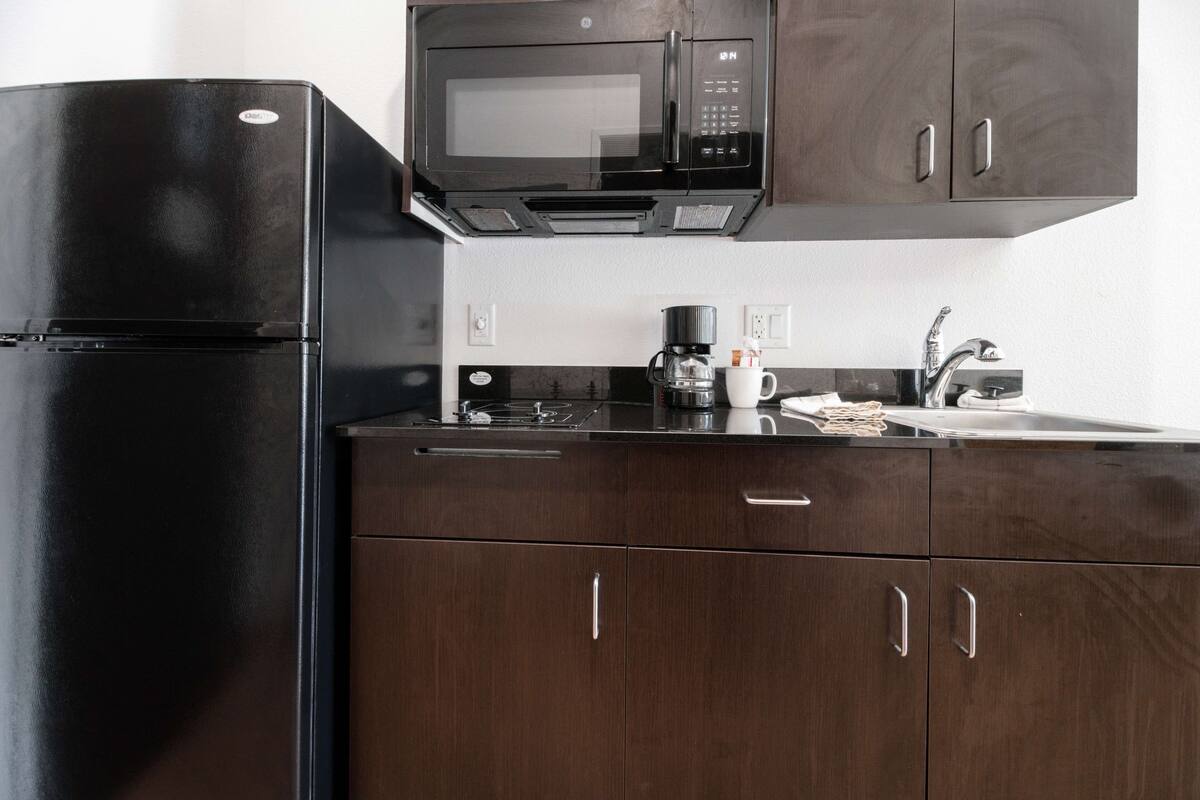 A kitchen with a black refrigerator, a microwave, and a coffee maker on the counter.