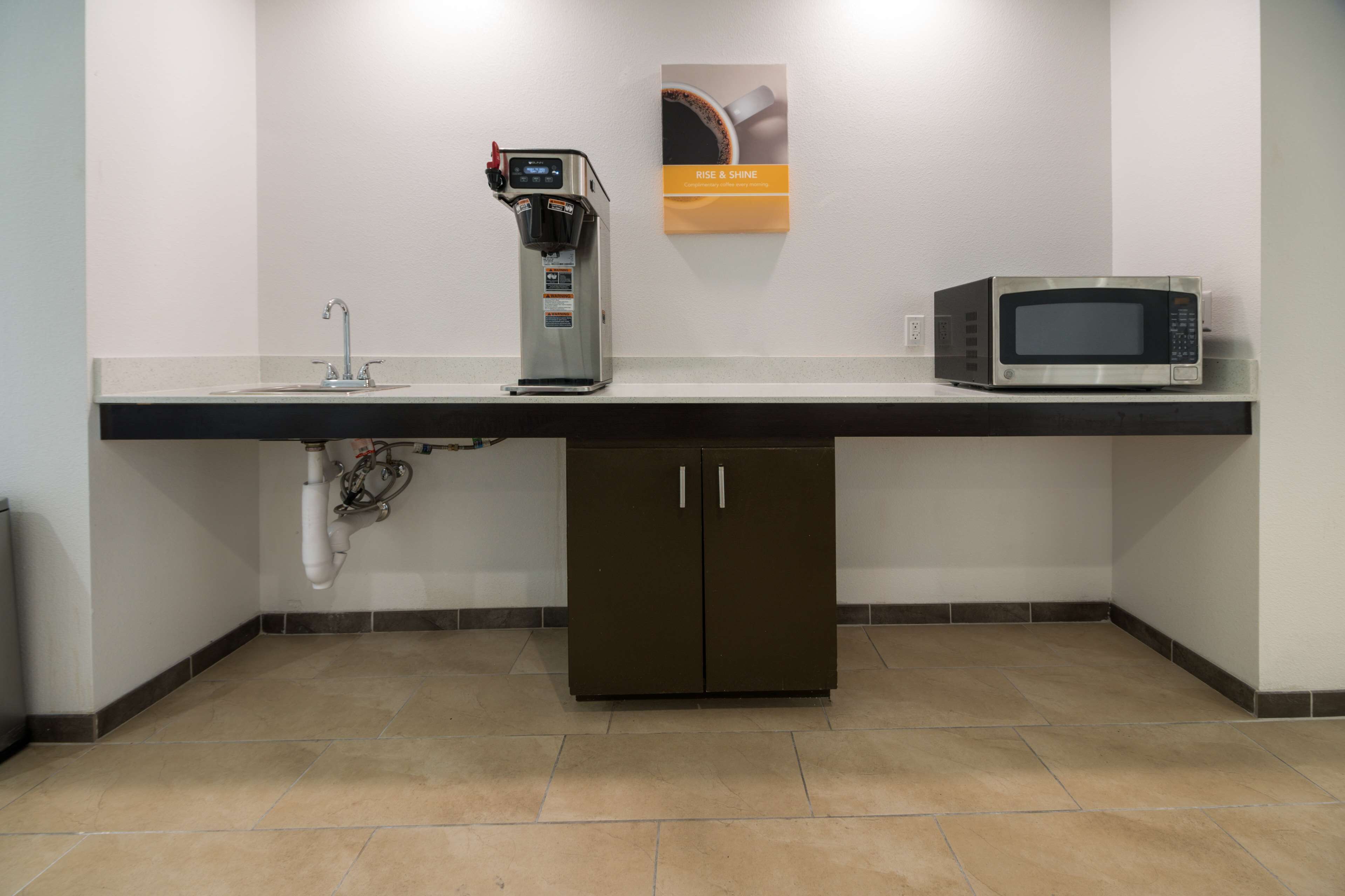 A kitchenette with a coffee machine, microwave, and cabinets.
