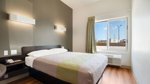 A hotel room with a bed, bedside table, lamp, and a window with curtains. - Studio 6 Corpus Christi, TX (Corpus Christi)