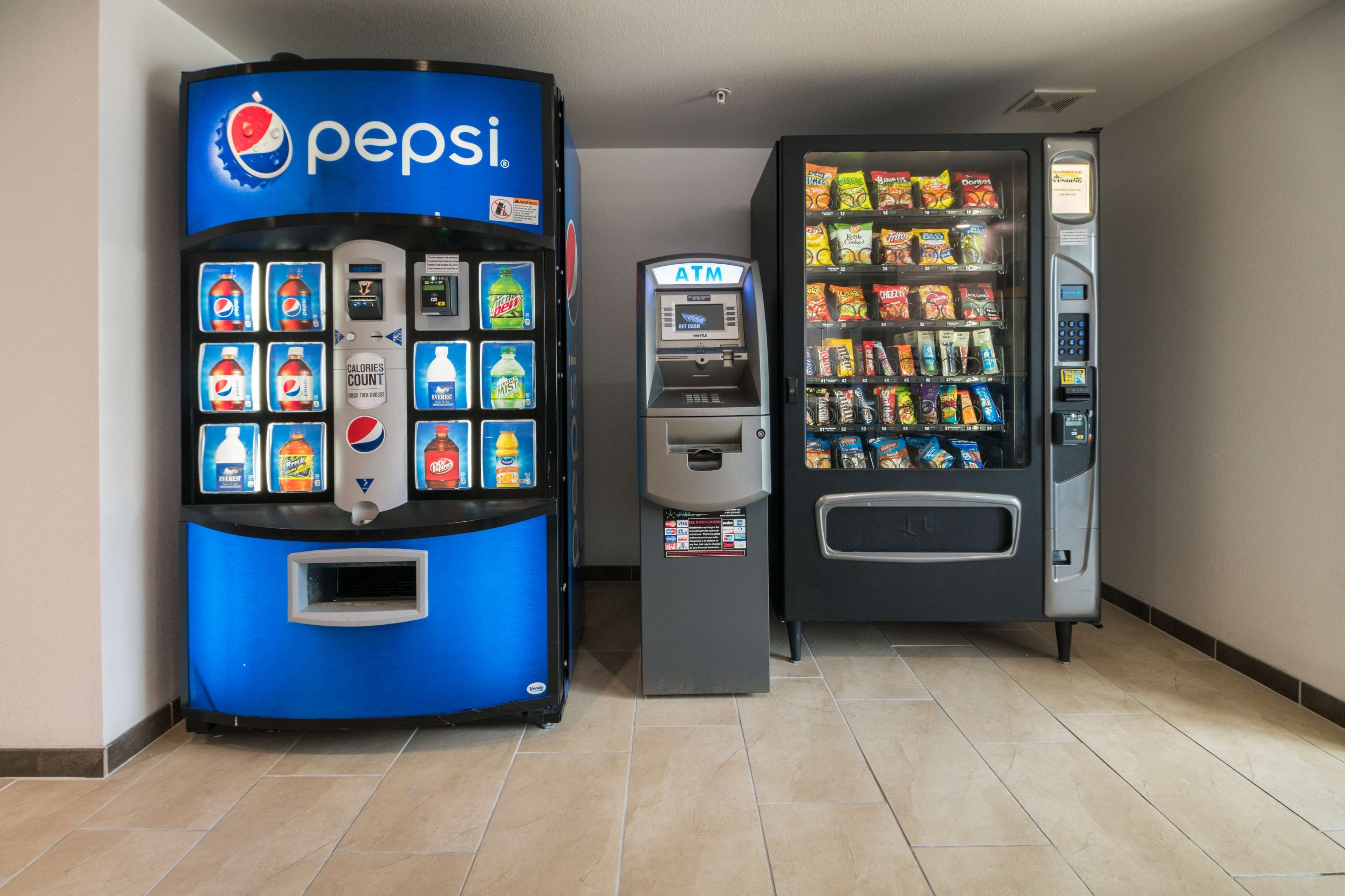 A Pepsi and a snack vending machine in a hallway.