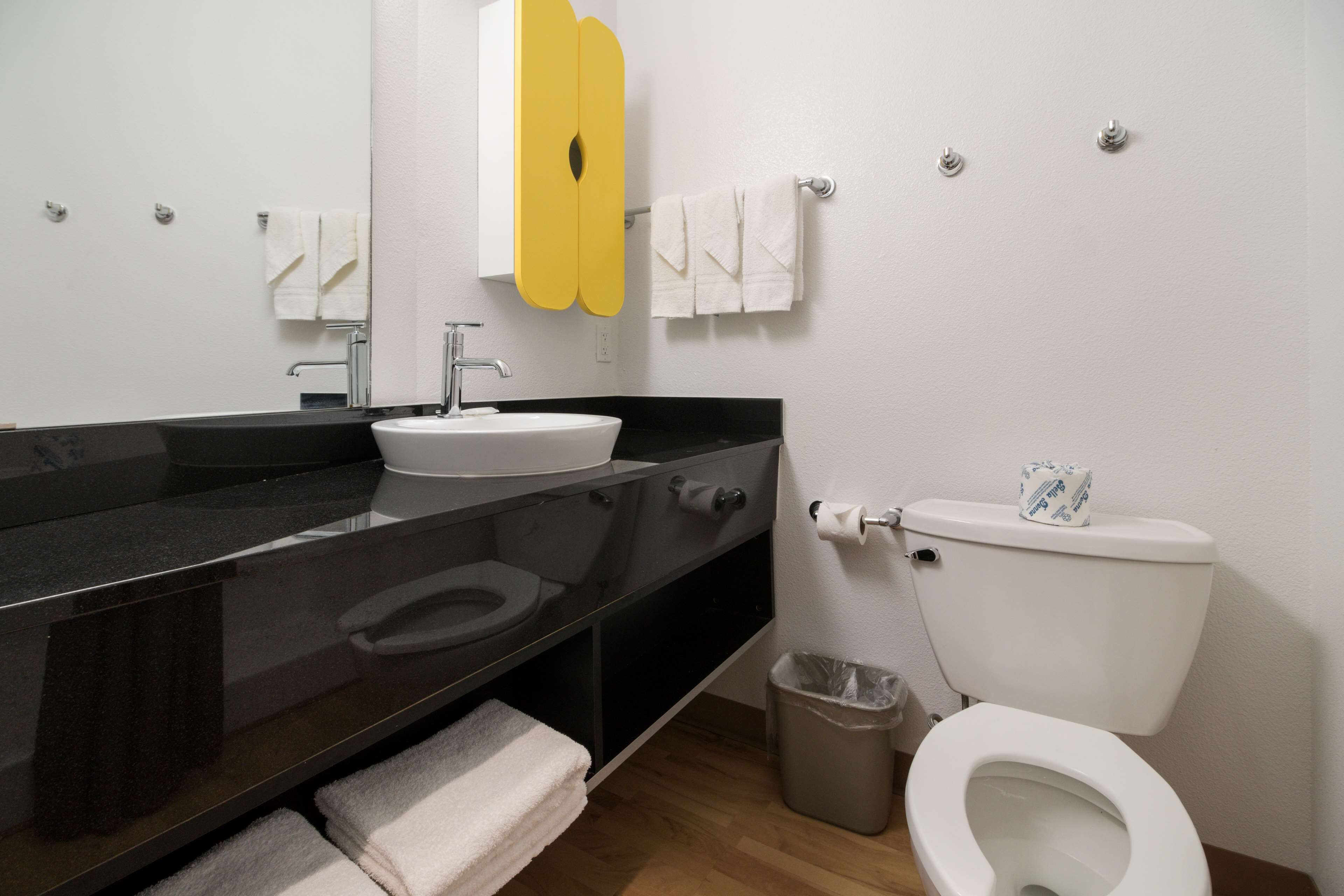 A modern bathroom with a black countertop, white sink, and toilet.