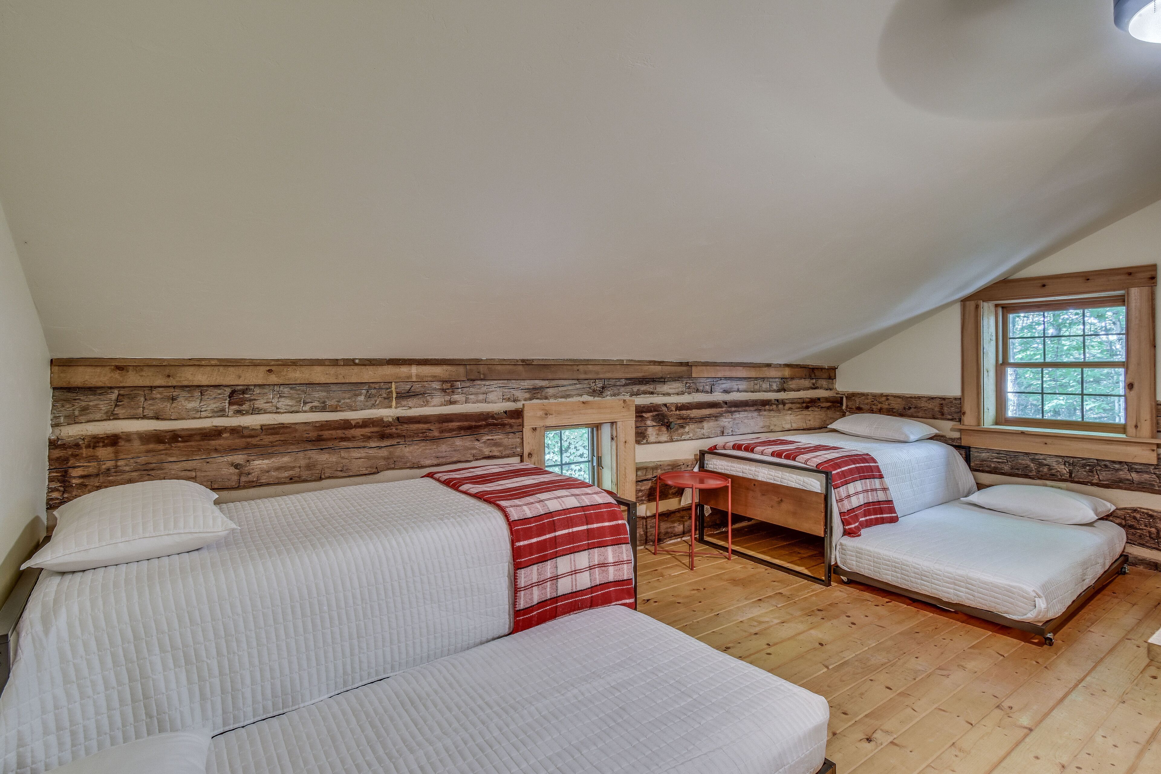 Um quarto de cabana aconchegante com duas camas, uma mesa pequena e uma janela.