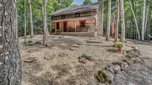 A rustic log cabin with a porch, surrounded by a forest. - Hand Hewn Log Cabin Newly Renovated, rustic-modern design (Egg Harbor)