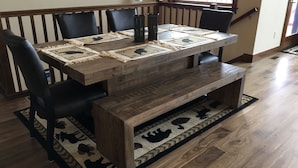 A dining table with a rustic design, surrounded by black chairs, set on a patterned rug. - Yellowstone Northern Views -- Gorgeous Home. One mile to Yellowstone! (Gardiner)