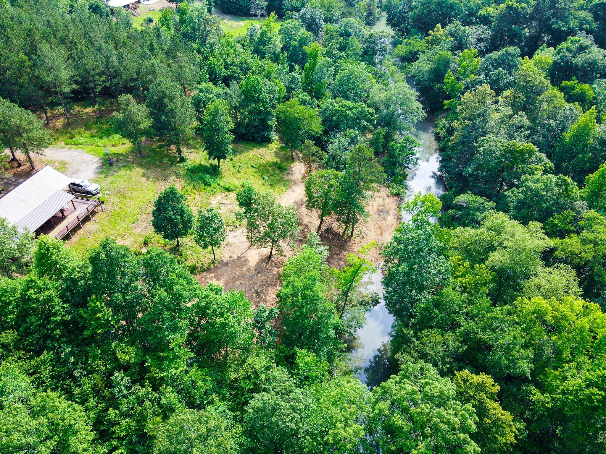 An aerial view of a forested area with a small building and a river.